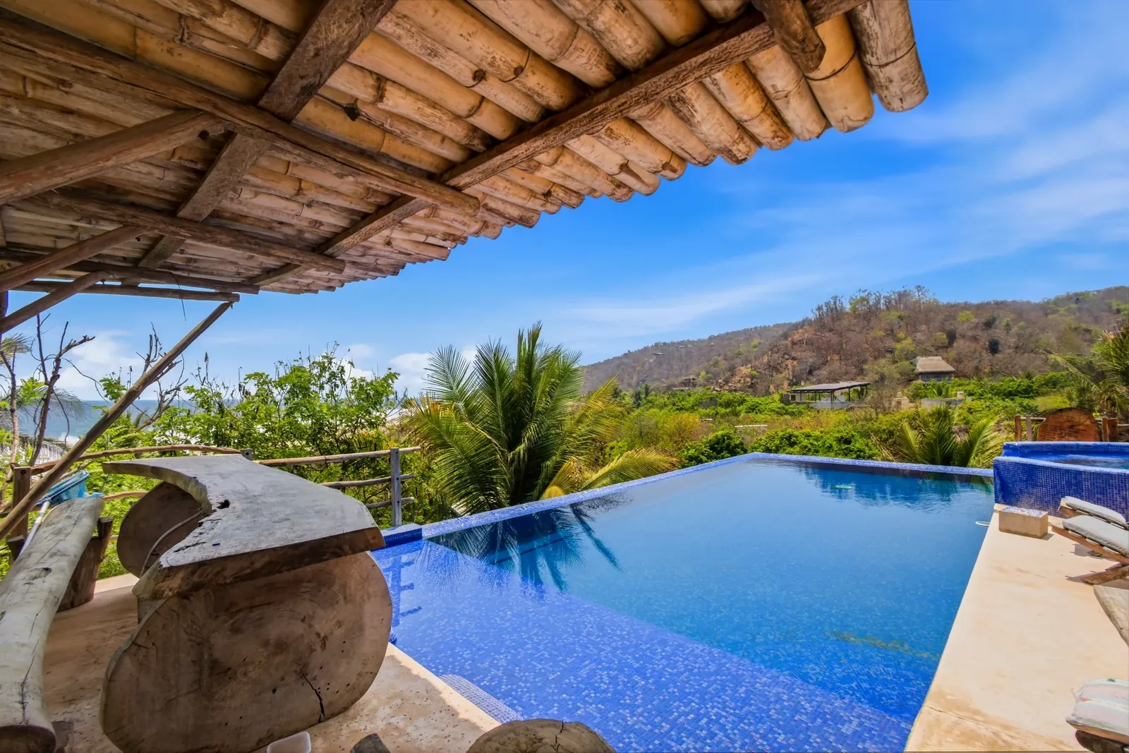 Infinity pool under a bamboo palapa with jungle and ocean views